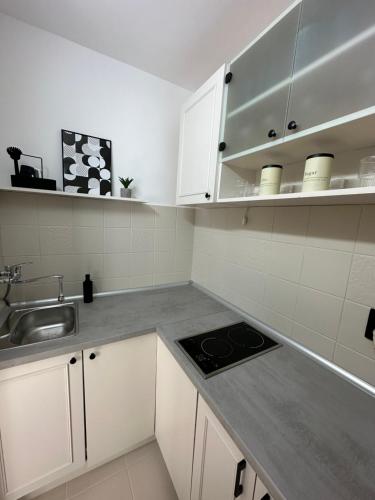 a kitchen with white cabinets and a sink at Banovo Brdo Premium in Čukarica