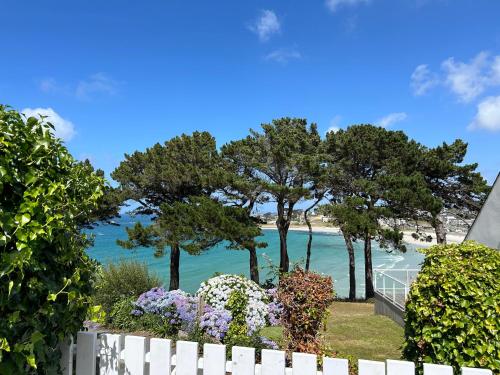 a white fence with trees and the beach in the background at Bellevues-Sur-Mer, à 100 m de la plage in Trévou-Tréguignec