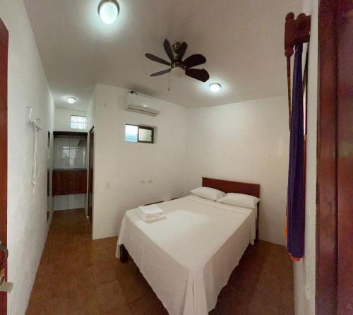 a bedroom with a white bed and a ceiling fan at Casa Romano Hostel in San Juan del Sur