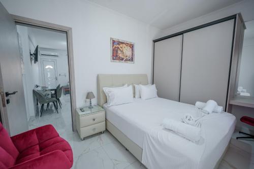 a white bedroom with a large bed and a red chair at Maria's Home in Kanallákion