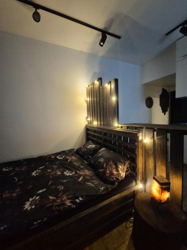 a bedroom with a bed with a headboard and lights at Zvaigžņu Apartment in Ogre
