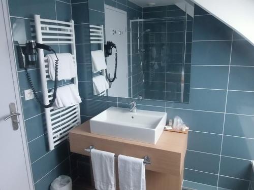 La salle de bains est pourvue d'un lavabo et d'un miroir. dans l'établissement Hôtel Restaurant Le Rive Gauche, à Joigny