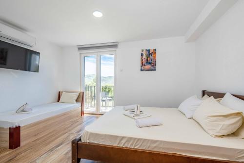 a white room with two beds and a window at Sumice Inn in Petrovac na Moru
