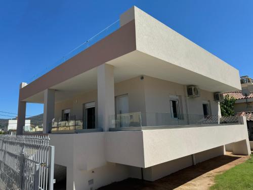 a white house with a balcony on the side at PUERTO VILLA, Best Location in Porto Rafti in Porto Rafti