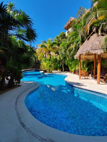 a swimming pool with blue water and palm trees at Aldea Zama Penthouse with Private Rooftop in Tulum