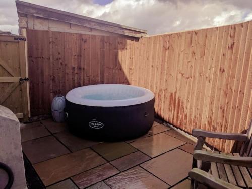 a bath tub sitting next to a wooden fence at Dawel Lodge with Hot Tub and Logfire in Llanferres