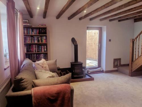 a living room with a couch and a wood stove at Dawel Lodge with Hot Tub and Logfire in Llanferres