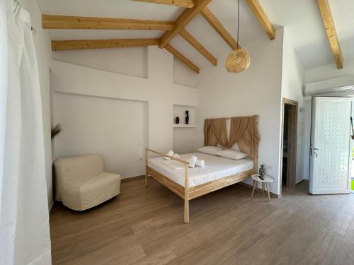 a bedroom with a bed and a chair at NikLuDin suites & studios in Laganas