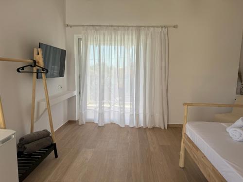 a white room with a bed and a window at NikLuDin suites & studios in Laganas