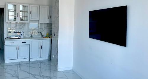 a kitchen with white cabinets and a flat screen tv at Апартаменты у моря с панорамным видом Золотой Берег in Odesa
