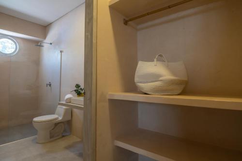 a bathroom with a toilet and a basket on a shelf at Nueva Apartasuite pleno centro in Santa Marta
