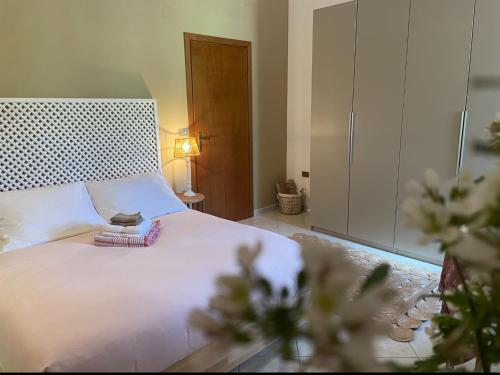 a bedroom with a white bed with a lamp and flowers at B&B La Vera Vita in Troviggiano