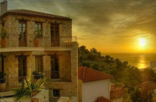 a painting of a building and a sunset at Anigraia in Paralion astros