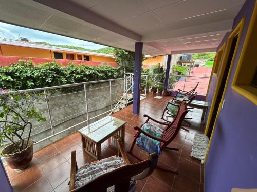 Un balcón con sillas y mesas. en Casa Romano Hostel, en San Juan del Sur