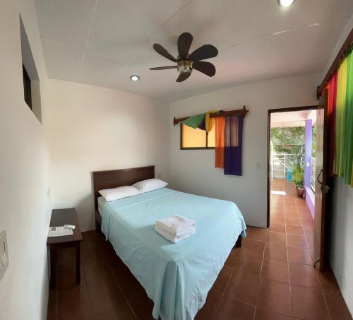 Un dormitorio con una cama y un ventilador de techo. en Casa Romano Hostel, en San Juan del Sur