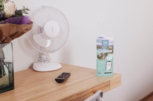 a white fan sitting on a table next to a remote control at Cityhotel am Domplatz Self-CheckIn in Klagenfurt