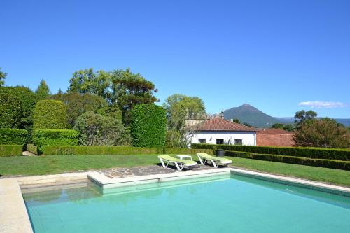 a swimming pool with two lounge chairs and a house at Casa do Campo - Turismo de Habitação in Celorico de Basto