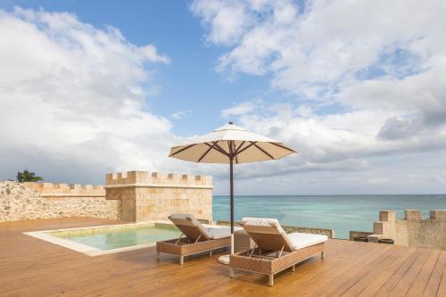 a patio with two chairs and an umbrella and the ocean at Sanctuary Cap Cana, a Luxury Collection Resort, Dominican Republic, Adult All-Inclusive in Punta Cana