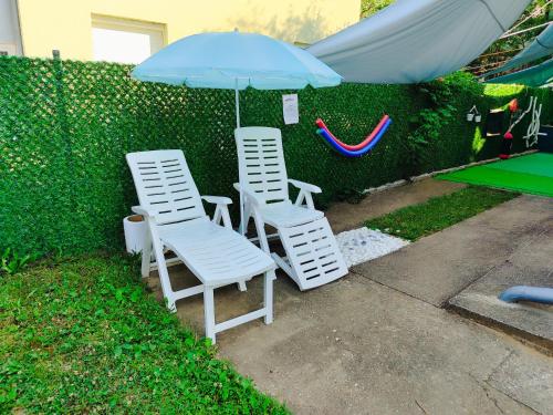 two white chairs and an umbrella next to a fence at Mitrovića kuća in Arandjelovac