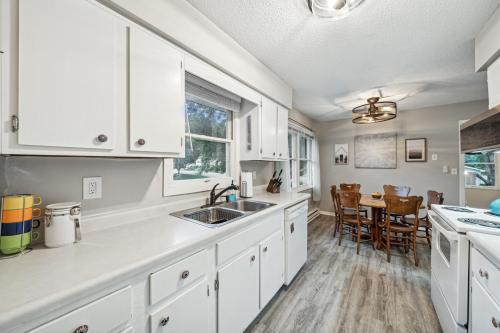 a kitchen with white cabinets and a dining table at Lilac Apartment - 5 Minutes to Downtown Stillwater in Stillwater