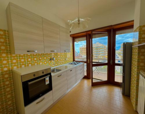 a kitchen with white cabinets and a large window at NINFEA SEAVIEW APARTMENT - Elegant, Bright and Spacious, Steps from the Sea & Station in Nettuno