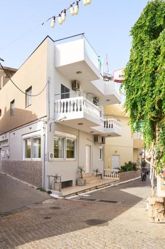 a white house with a balcony on a street at Malia Boutique Studios in Malia