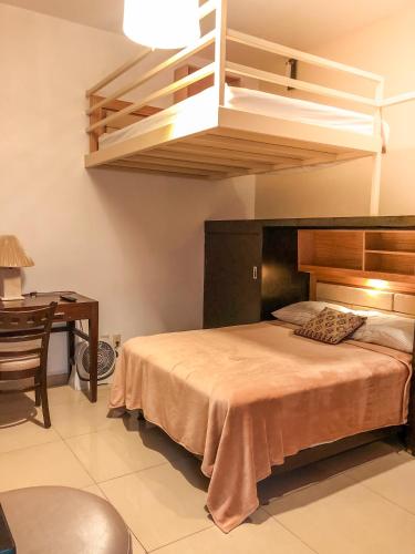 ein Schlafzimmer mit einem Bett mit hölzernem Kopfteil und einem Schreibtisch in der Unterkunft Suites Hamburgo in Mexiko-Stadt