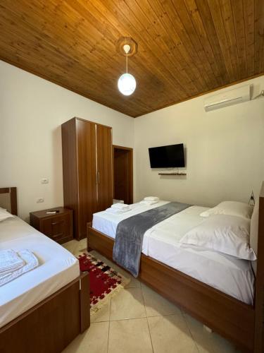 a bedroom with two beds and a flat screen tv at MEROLI Guesthouse - UNESCO quarter in Berat