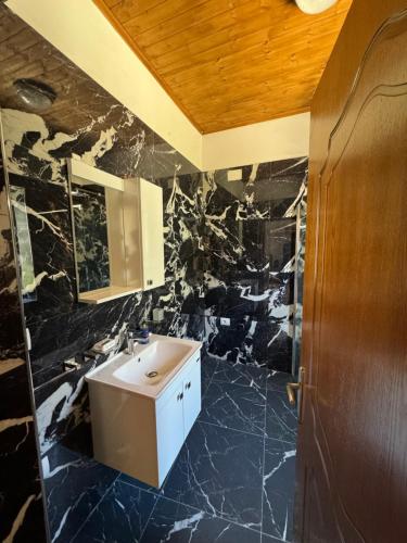 a bathroom with a sink and a black marble wall at MEROLI Guesthouse - UNESCO quarter in Berat