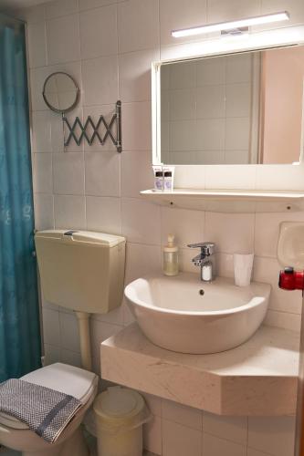 a bathroom with a sink and a toilet and a mirror at Malia Boutique Studios in Malia