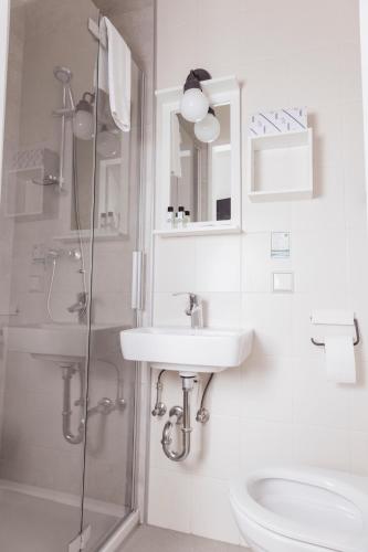 a white bathroom with a sink and a shower at Cityhotel am Domplatz Self-CheckIn in Klagenfurt