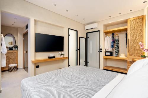 a bedroom with a large bed and a flat screen tv at Legato Spa Suites With Private Pool in Naxos Chora
