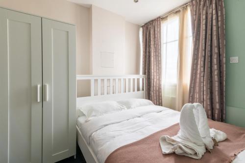 une chambre avec un lit avec des draps blancs et une fenêtre dans l'établissement Le Gentilléen - Bel appartement à Gentilly pour 4, au Kremlin-Bicêtre