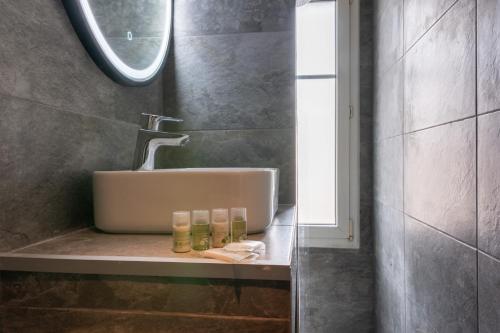 - un lavabo dans la salle de bains avec 3 bouteilles sur un comptoir dans l'établissement Le Gentilléen - Bel appartement à Gentilly pour 4, au Kremlin-Bicêtre