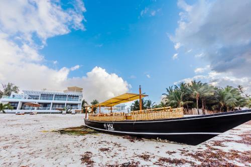 a boat sitting on the beach in front of a building at YU Resort in Msambweni
