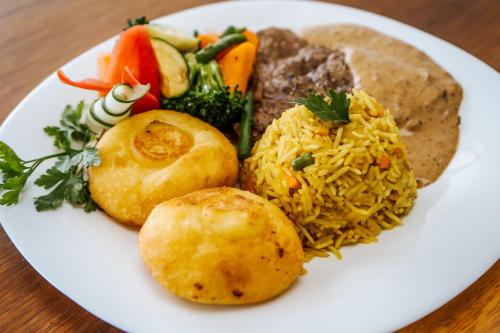a plate of food with rice and vegetables on a table at YU Resort in Msambweni