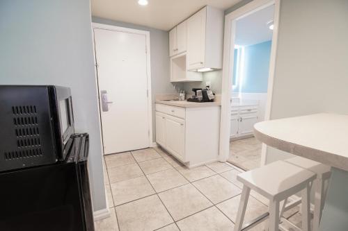a kitchen with white cabinets and a table and stool at Oceanfront Litchfield Inn in Pawleys Island