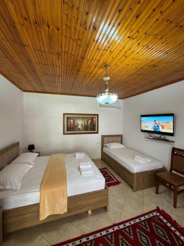 a bedroom with two beds and a flat screen tv at MEROLI Guesthouse - UNESCO quarter in Berat