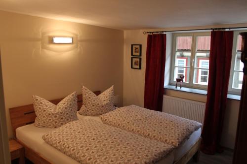 een slaapkamer met een bed met kussens en een raam bij Ferienwohnungen Im Alten Handelshof in Quedlinburg