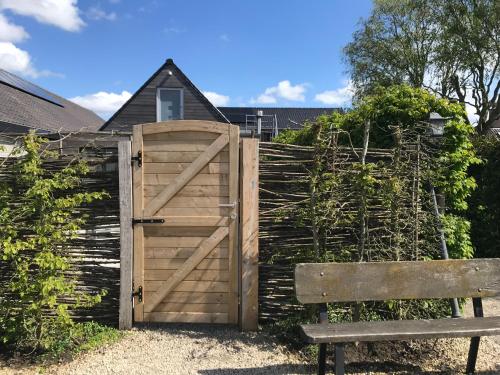 a wooden gate and a bench next to a fence at The Suite Escape Suite Wood in Sint-Lievens-Houtem