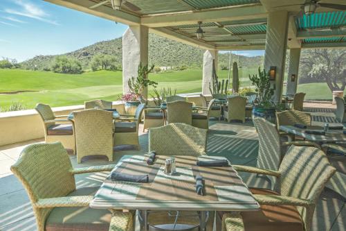 a patio with tables and chairs on a golf course at Starr Pass Golf Suites in Tucson
