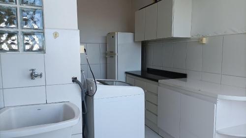 a white kitchen with a sink and a refrigerator at Apto 2Q Grande e Espaçoso in Curitiba