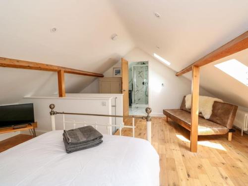 a bedroom with a bed and a couch and a television at The Coach House in Cranwell