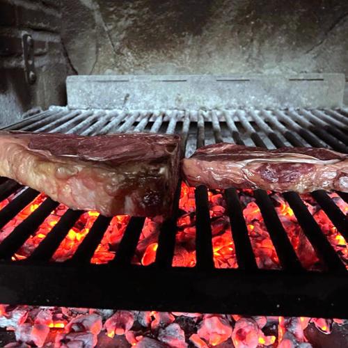 two pieces of meat sitting on top of a grill at Hotel Rural y Restaurante, Rinconcito de Gredos in Cuevas del Valle