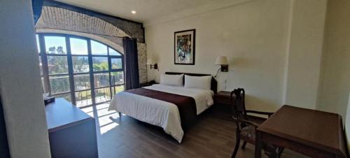 a bedroom with a bed and a desk and a window at SANTA CECILIA LA MORA HUASCA in Huasca de Ocampo