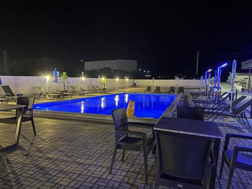 a swimming pool at night with chairs and a table at Hotel FOCUS in Prilep