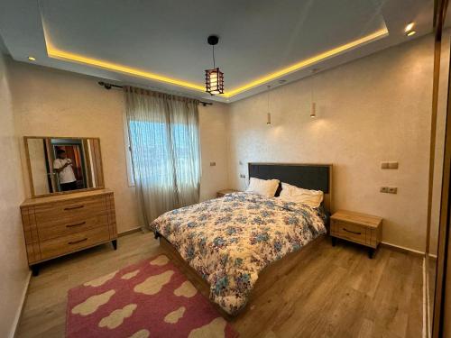 a bedroom with a bed and a dresser and a mirror at Très Bel Appartement familial sur Rabat Temara PLAGES avec Piscines in El Harhoura