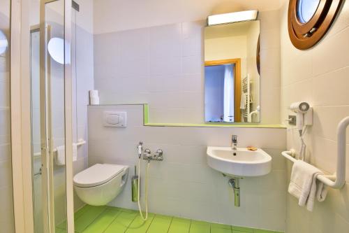 a bathroom with a sink and a toilet and a mirror at Hotel Trieste Mare in Lignano Sabbiadoro