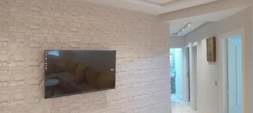 a flat screen tv mounted on a brick wall at Nador al jadid chaabi in Nador