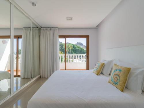 a bedroom with a large white bed with a large window at Bungalows Caribe in Puerto Rico de Gran Canaria